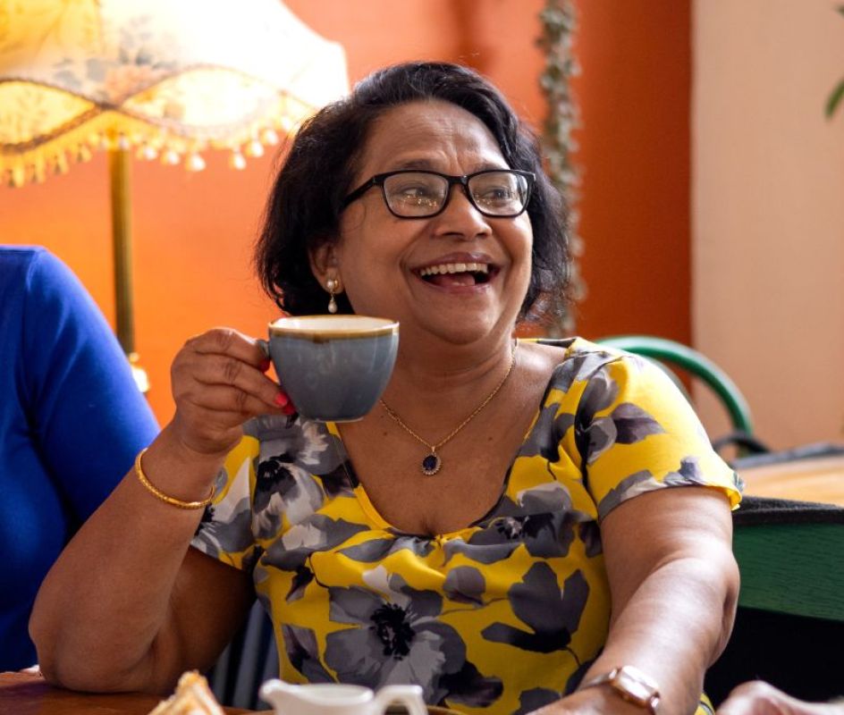 photo of a female enjoying tea raising her cup in 'cheers'